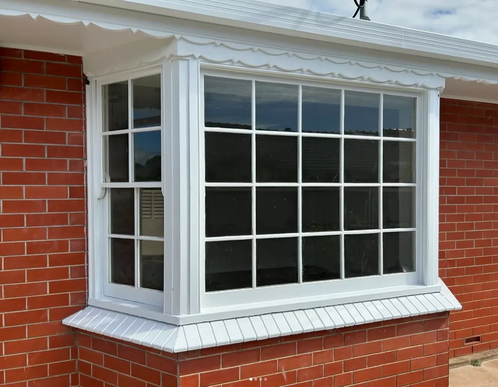 Bay window with freshly painted white timber trims on a red brick wall