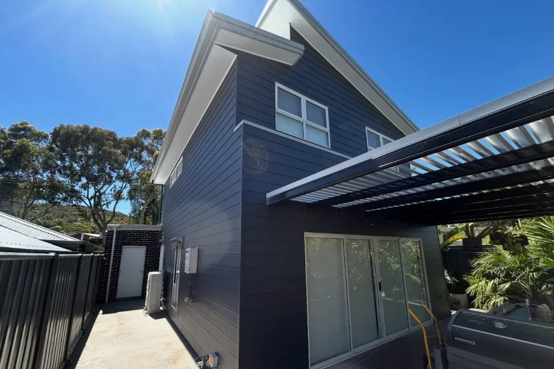 Charcoal painted cladding on a rear extension with a white pergola