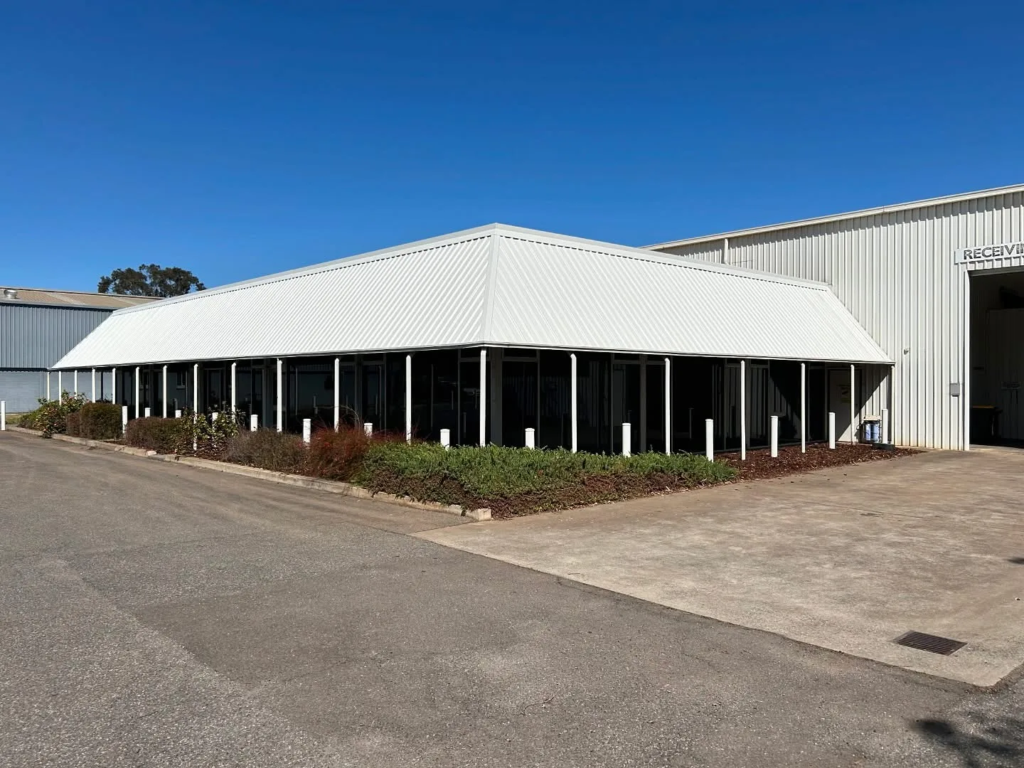 Commercial warehouse exterior repainted white with a roller door