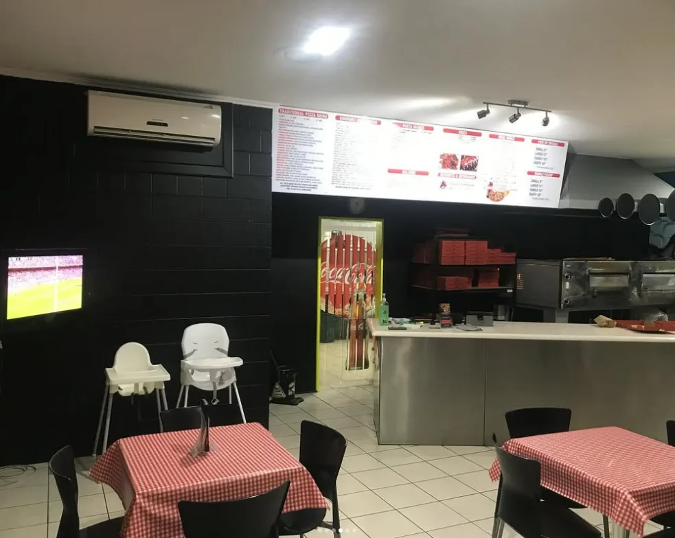 Pizza shop interior with walls painted black and pendant lights
