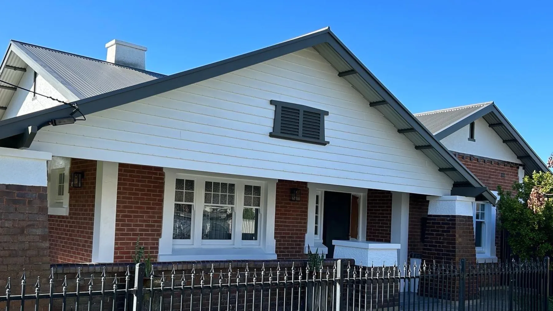 Red brick bungalow exterior with freshly repainted white trim around the windows and eaves