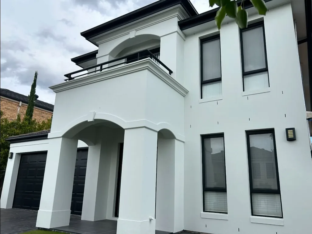 Two-storey rendered home repainted white with dark window frames