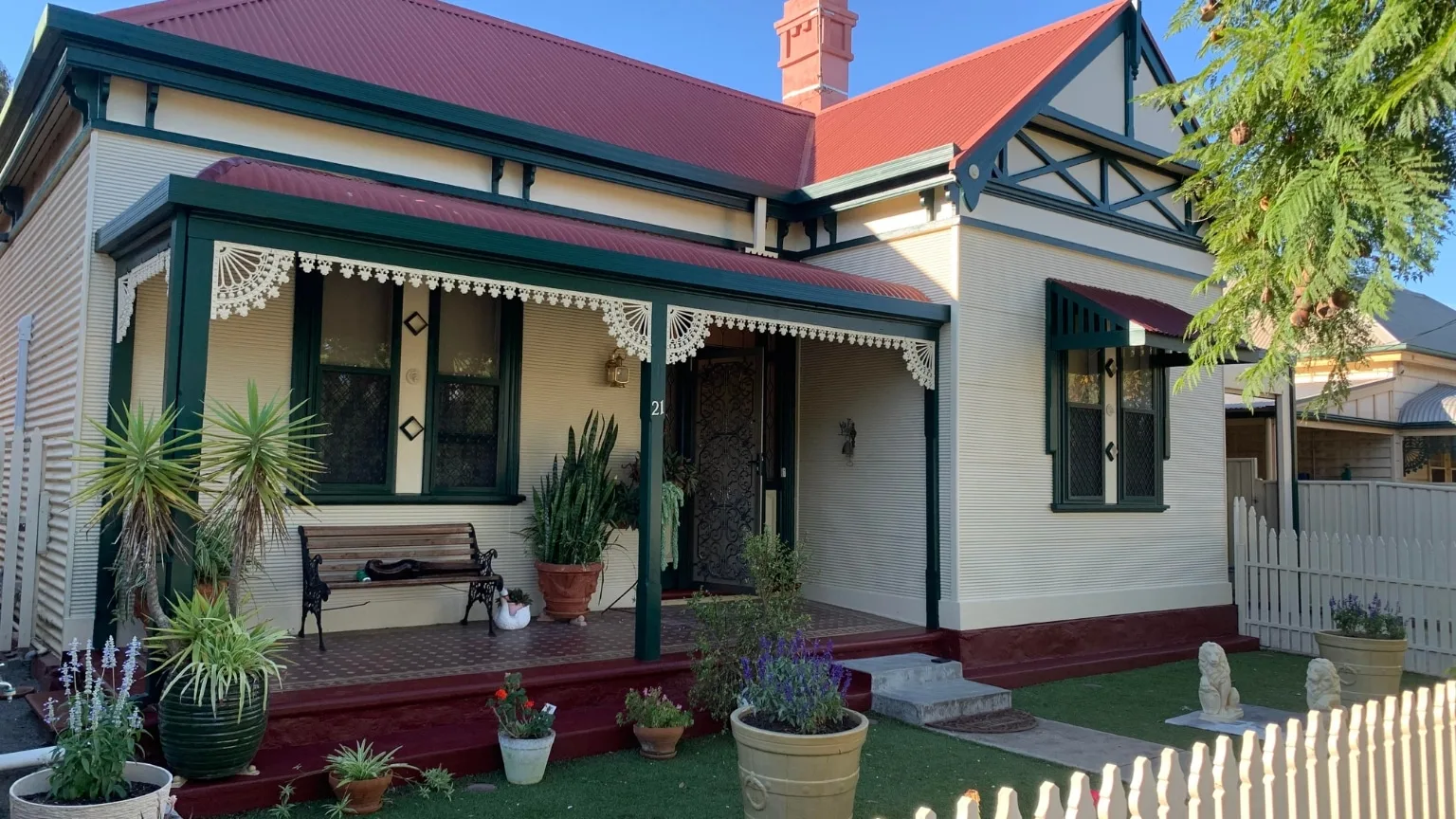 Rendered villa exterior painted cream with green trims under a red tiled roof