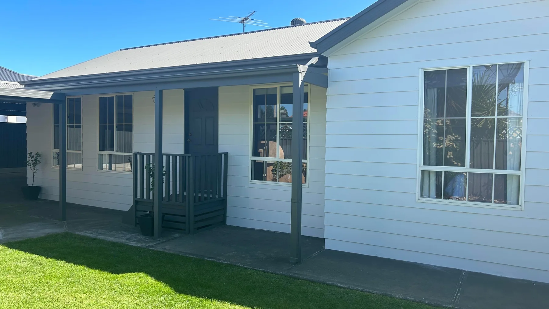 Weatherboard cottage painted white with a grey roof and verandah